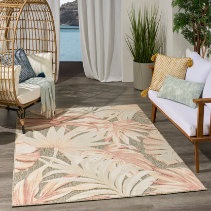 Pastel botanical rug with pink and cream leaves, rattan hanging chair and white sofa in a coastal lounge.