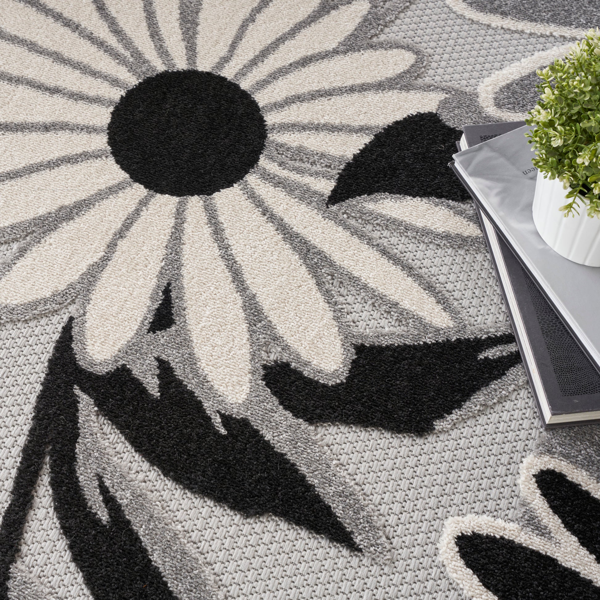 Gray floral area rug with oversized white petals and black centers; plush shag texture.