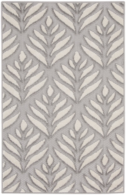 Gray rug with cream fern-like leaf pattern, textured woven surface, modern botanical design.