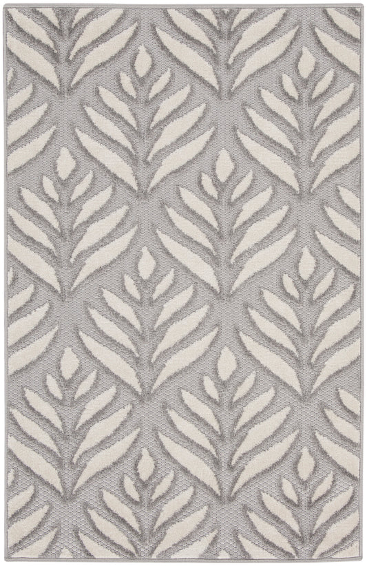 Gray rug with cream fern-like leaf pattern, textured woven surface, modern botanical design.