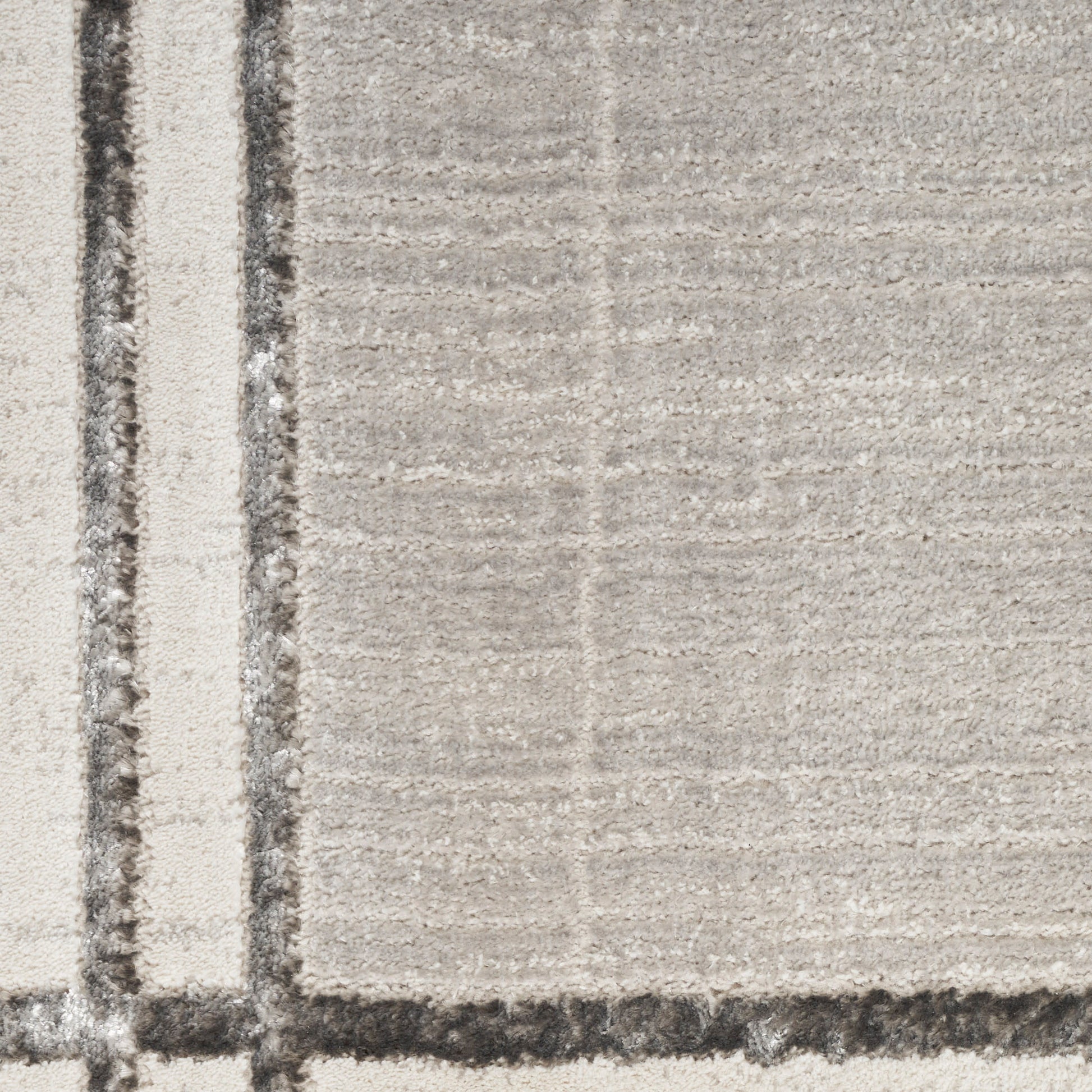 Beige rug with subtle grid pattern and a bold vertical border stripe along the left edge; modern textured look.