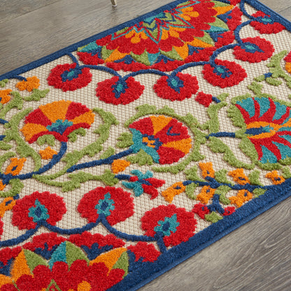Colorful floral area rug with red, orange, teal and lime green motifs on a cream background; blue border on a wooden floor.