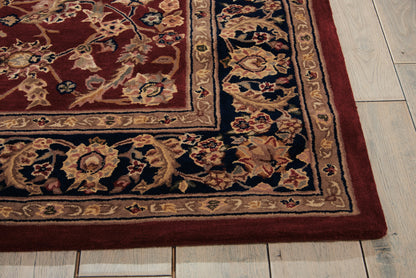 Rectangular oriental rug with burgundy field, intricate beige-gold border and floral motifs on a light wood floor.