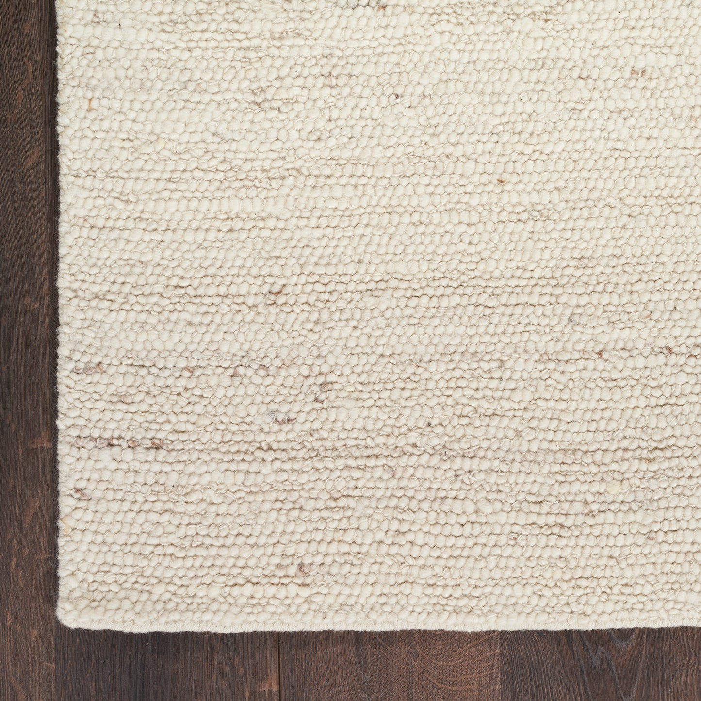Cream boucle loop-pile rug with a textured surface on dark hardwood floor; rectangular, farmhouse-style.