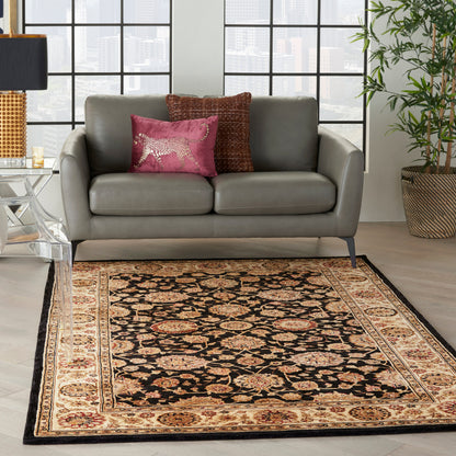 Grey leather loveseat with pink and brown cushions; black-and-cream oriental rug in a bright city living room.