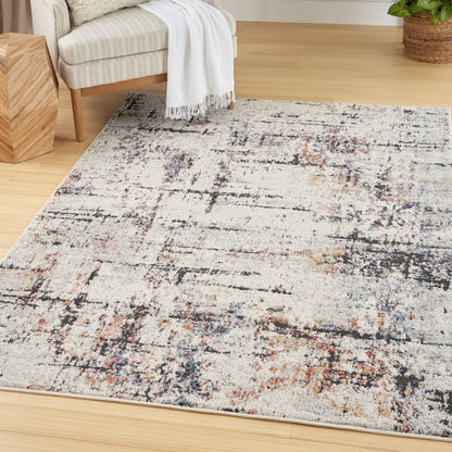 Rectangular abstract rug in cream, beige, navy and rust on a wood floor; modern distressed pattern for a cozy living room.