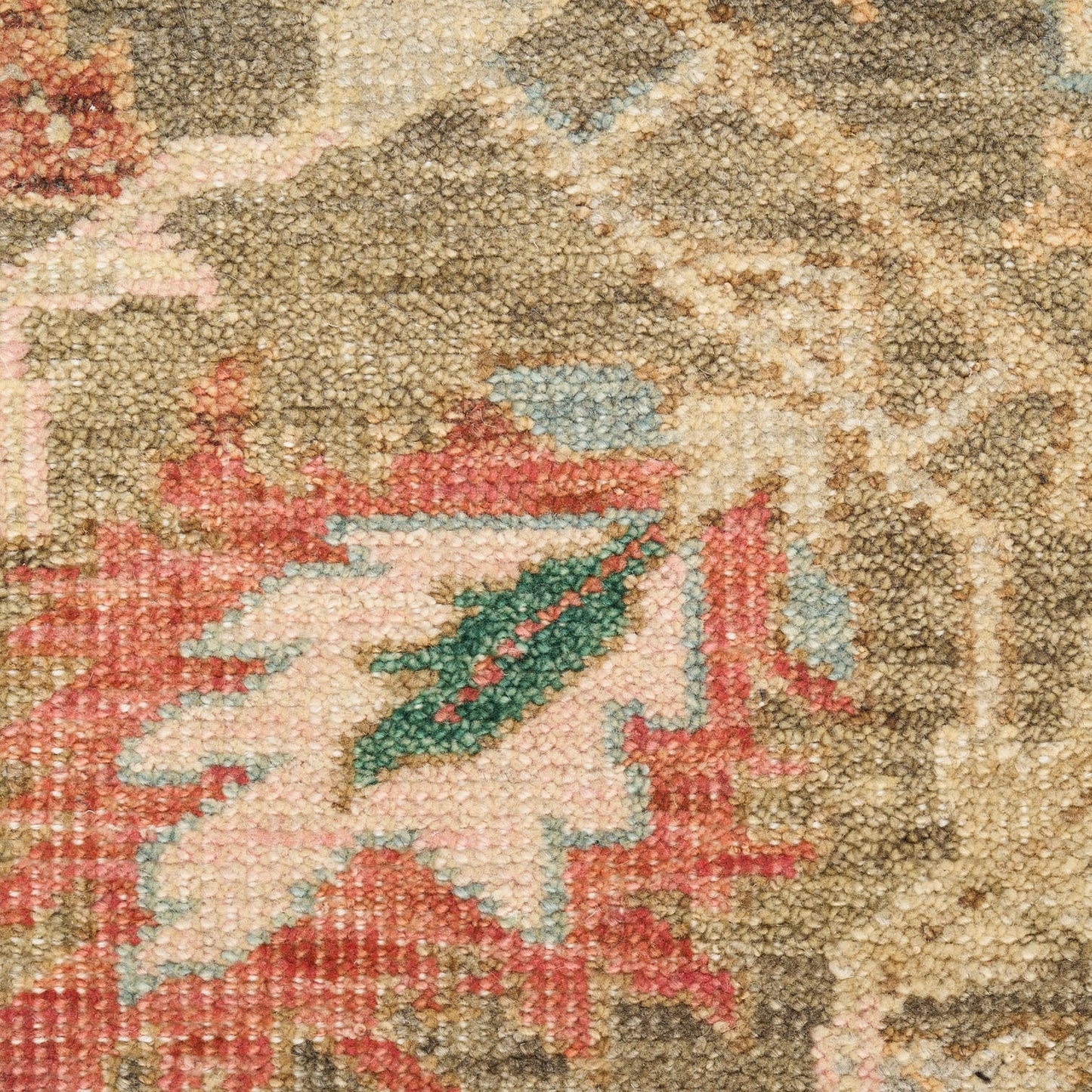 Close-up of an oriental rug with beige background, pink-red floral motif and blue-green accents.