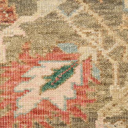 Close-up of an oriental rug with beige background, pink-red floral motif and blue-green accents.