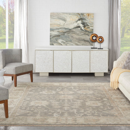 Contemporary living room with textured light rug, white sideboard, abstract art, rounded wood speakers, beige sofa and gray armchairs.