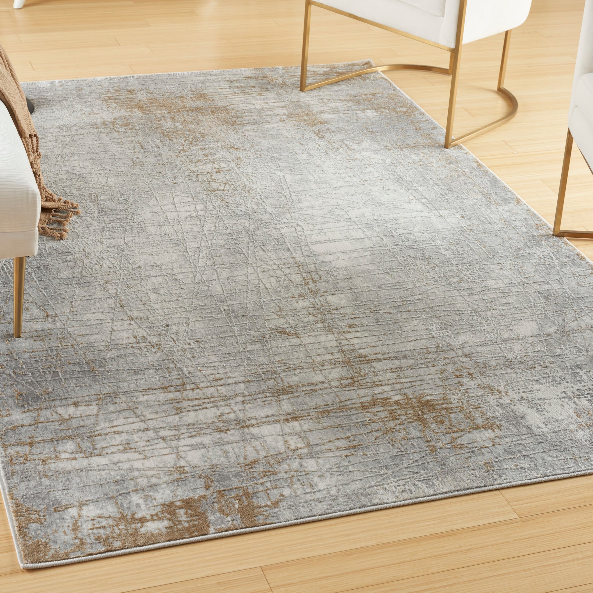 Rectangular gray distressed area rug with abstract rust-brown pattern on light hardwood floor in a modern living room.