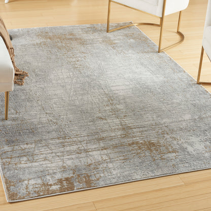 Rectangular gray distressed area rug with abstract rust-brown pattern on light hardwood floor in a modern living room.