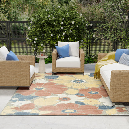 Outdoor woven rattan seating with white cushions, blue pillows, a colorful floral rug, and a round side table.
