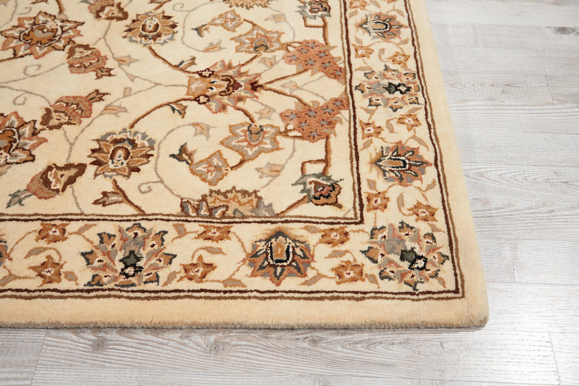 Cream oriental rug with brown floral border and rust accents on a light wood floor.