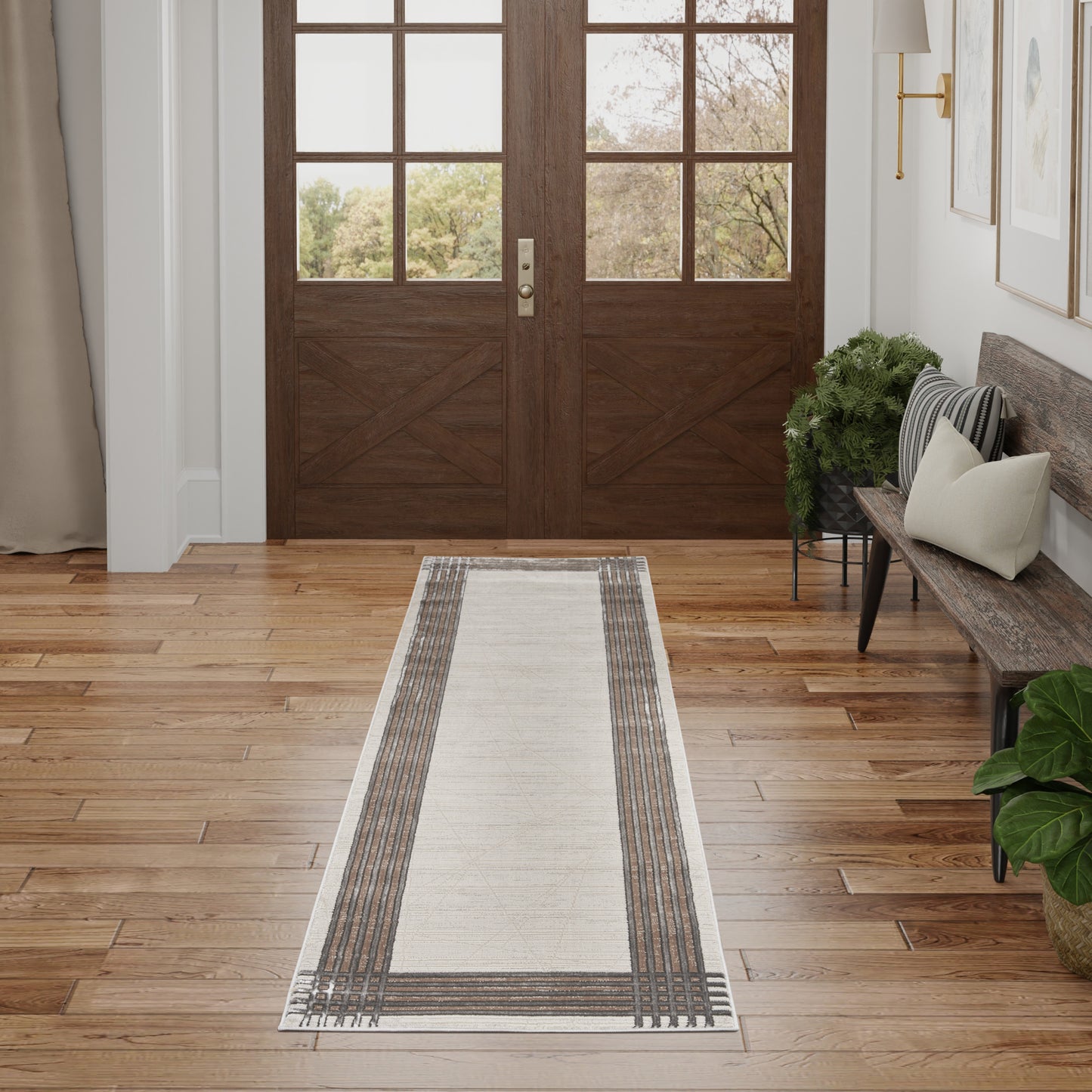Cream hallway runner rug with brown striped borders on a wood floor beside glass-paneled double doors.