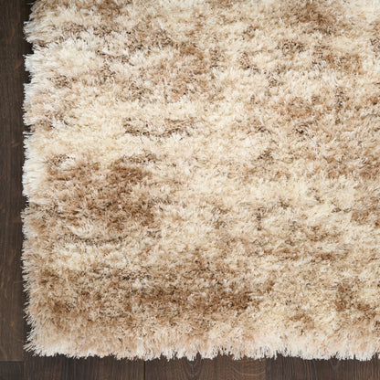 Beige shag rug with cream and tan fibers on dark hardwood floor; plush, fluffy rectangular area rug.