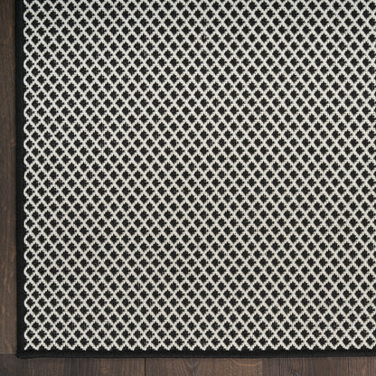 Rectangular rug with cream lattice weave on charcoal background, dark wood edge framing.