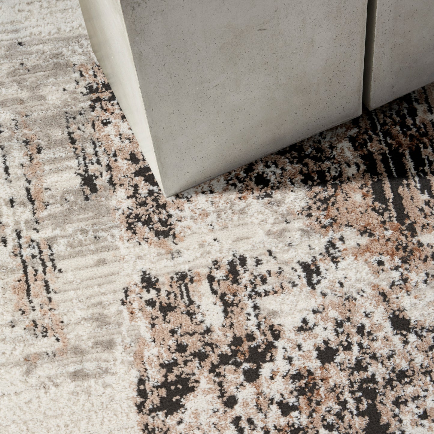 Light gray concrete-look rug with a beige, black and brown abstract pattern.