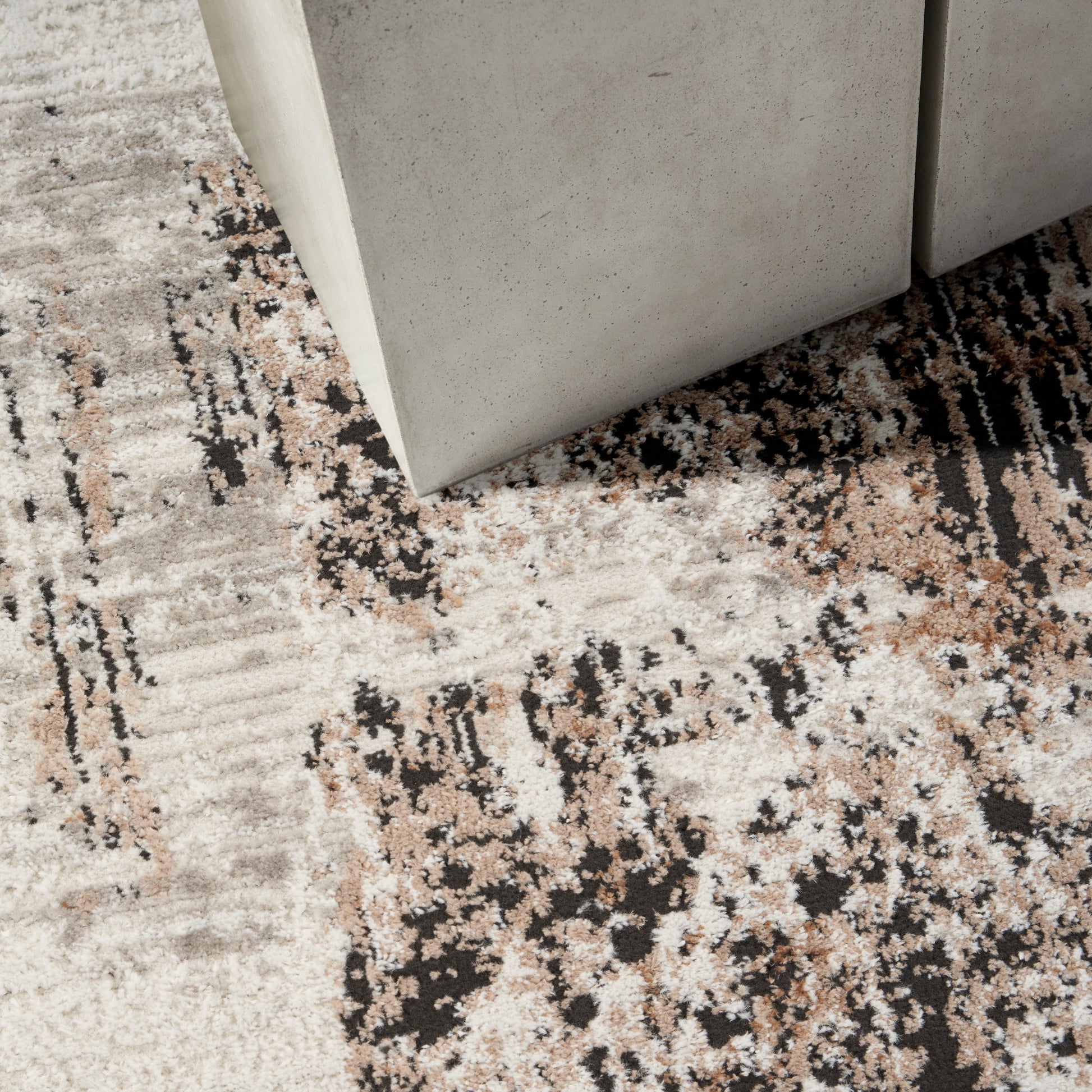 Light gray concrete-look rug with a beige, black and brown abstract pattern.