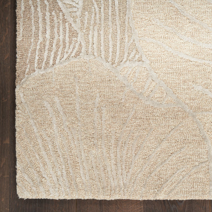 Beige textured area rug with subtle light gray abstract leaf/branch pattern on dark wood floor.