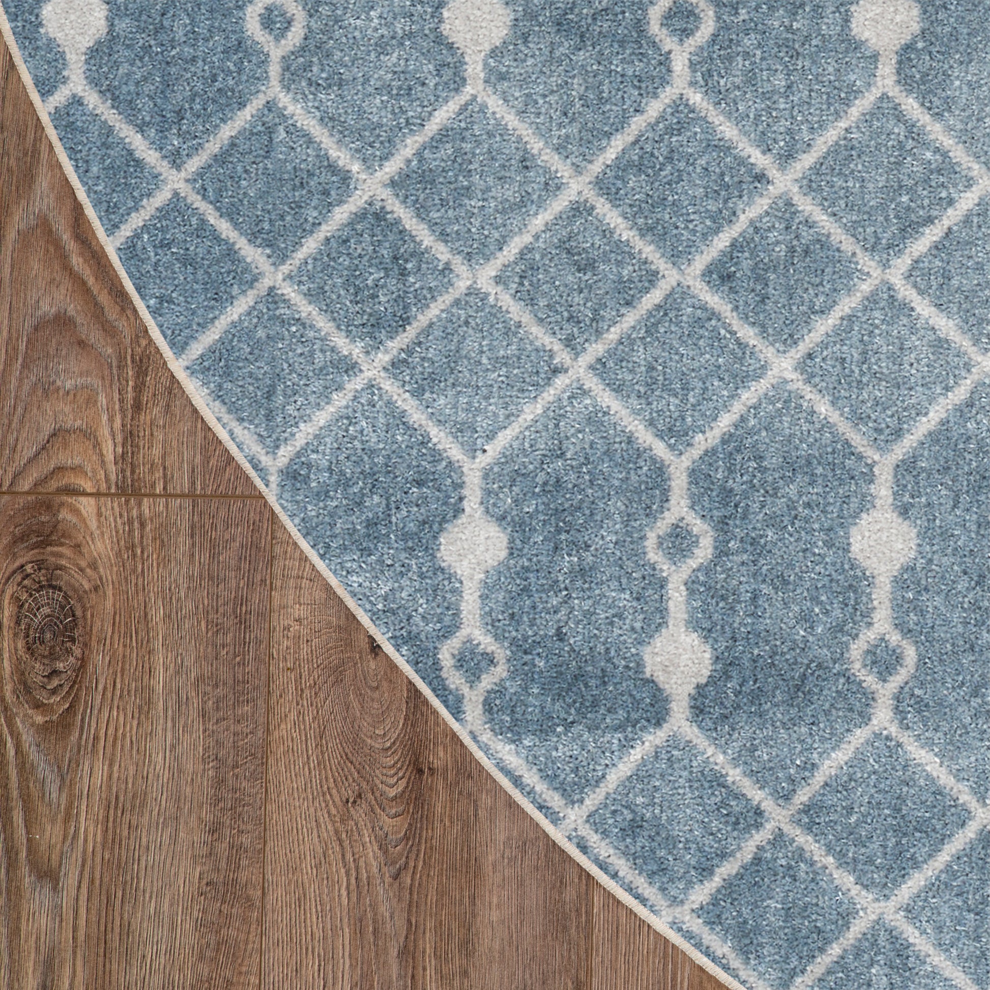 Blue rug with white lattice trellis pattern on wood floor, curved edge.