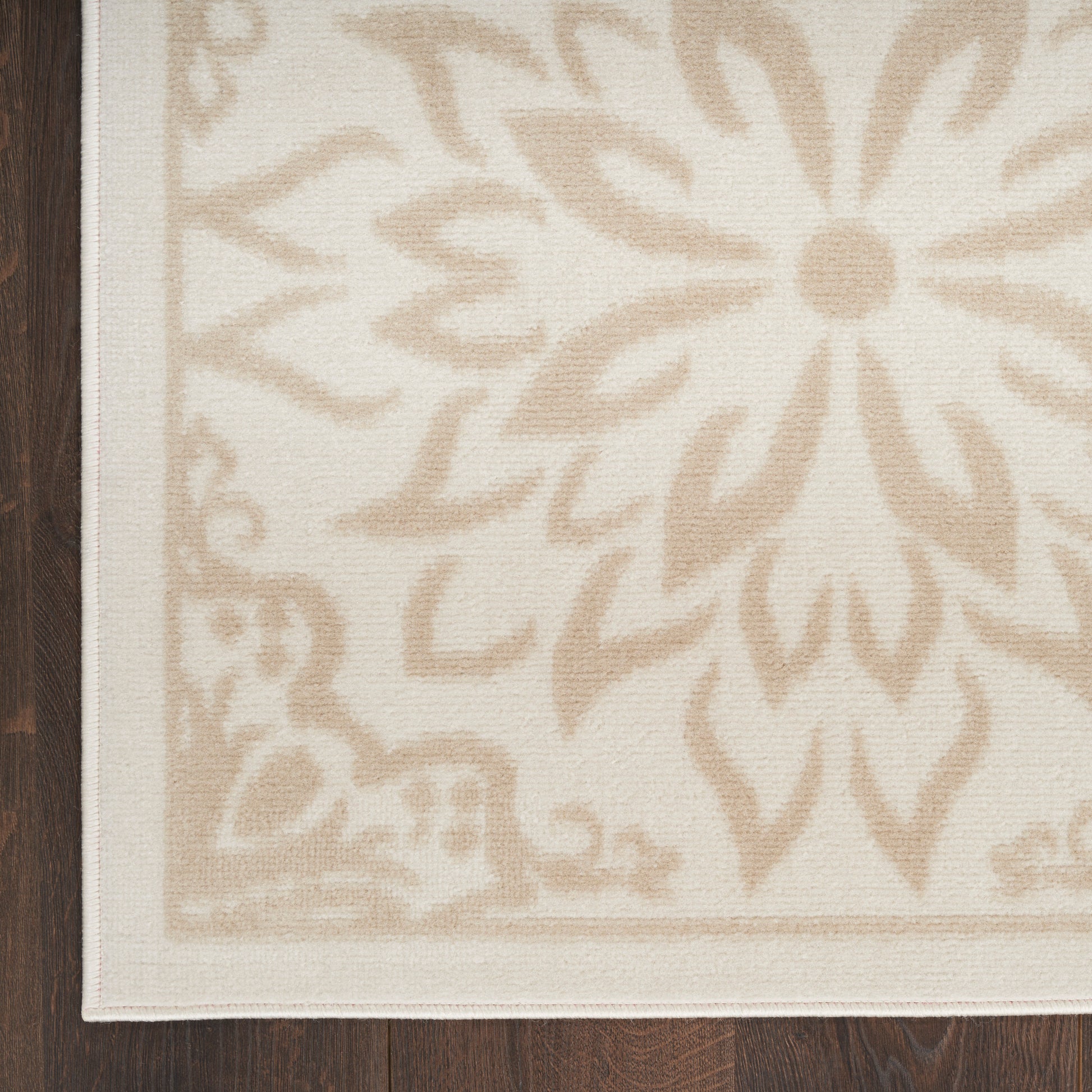 Rectangular cream rug with subtle beige damask floral pattern and light border on dark wood floor.
