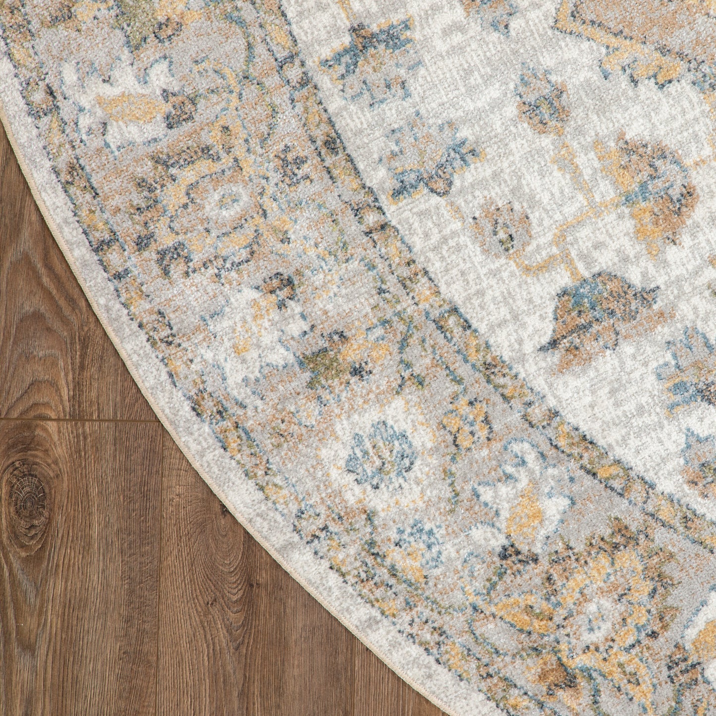 Round vintage floral area rug in ivory with blue and mustard accents on wood floor.