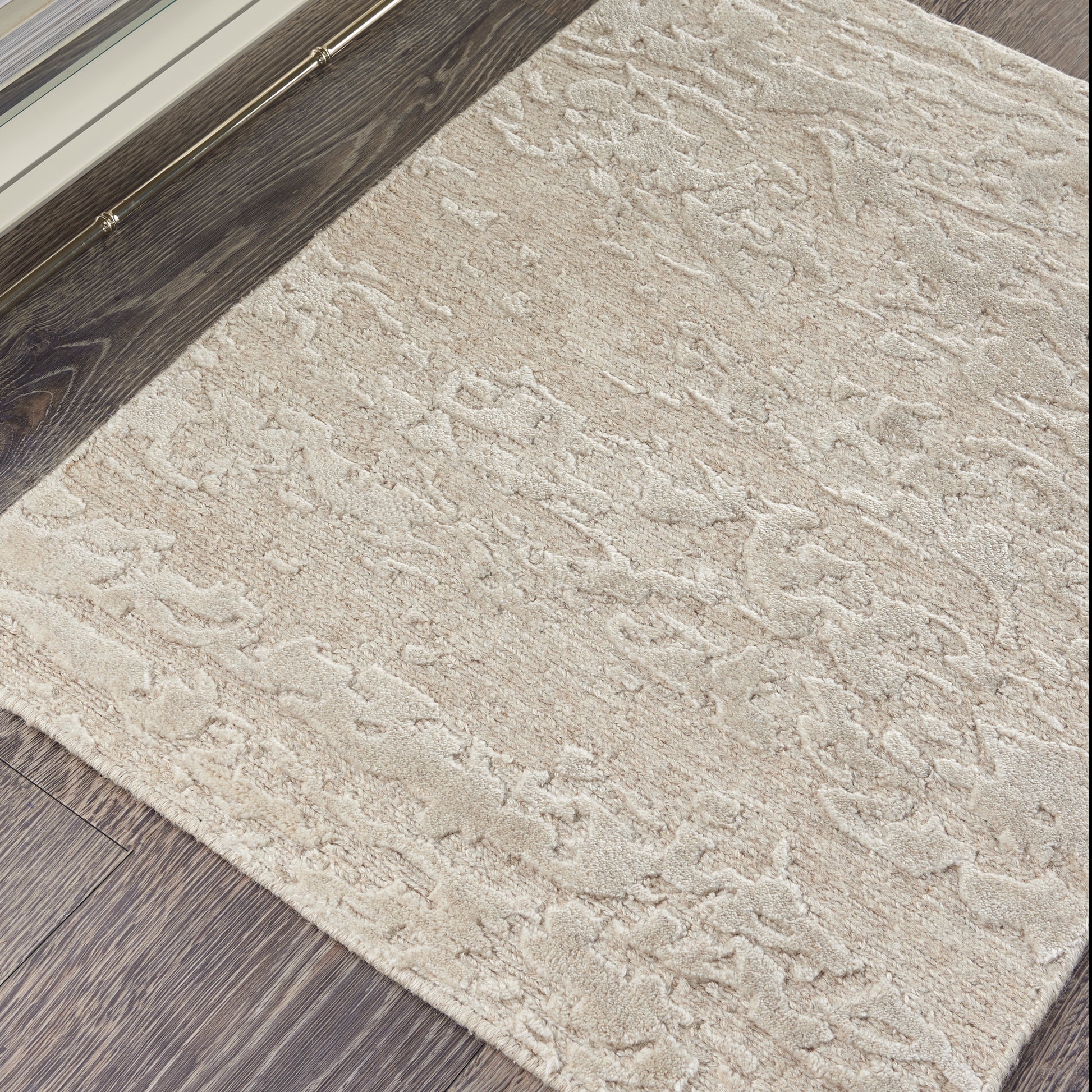 Beige textured rectangular area rug with soft plush pile, cream pattern, ideal for living room on dark wood floors.
