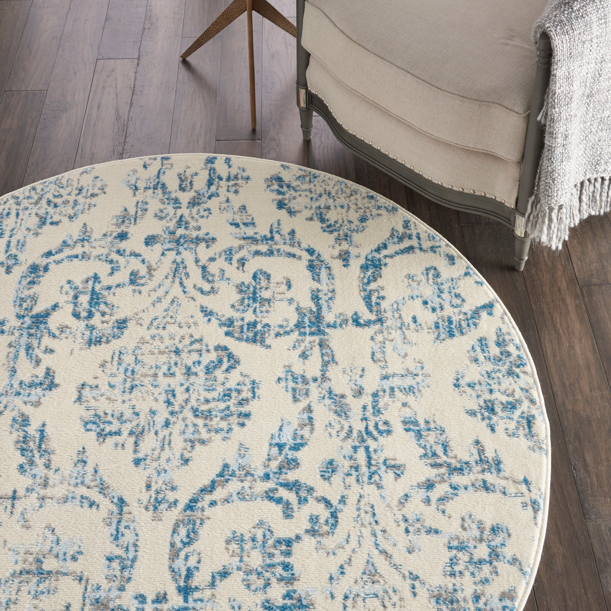 Round cream woven rug with blue distressed damask pattern; classic floral medallion for living room decor.