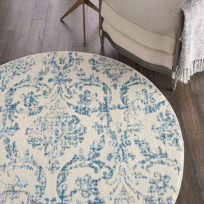 Round cream woven rug with blue distressed damask pattern; classic floral medallion for living room decor.