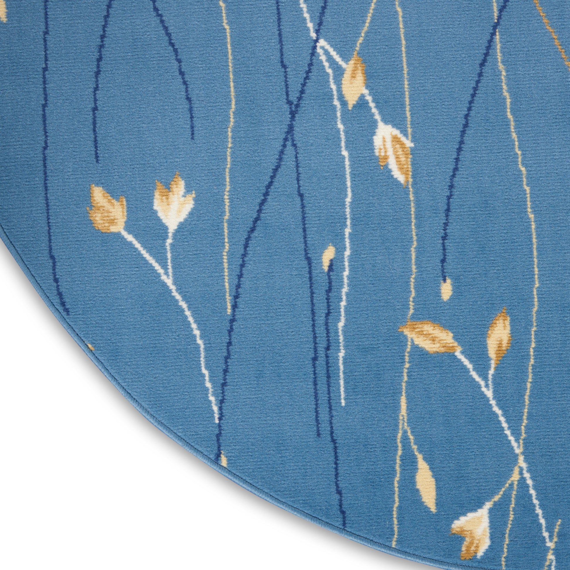 Blue rug with white and dark blue vine stems and gold leaves, curved edge visible.