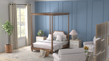 Vintage rug on the floor of a bedroom scene with a natural wood canopy bed, white linens, blue paneled wall, white nightstands & lamps.