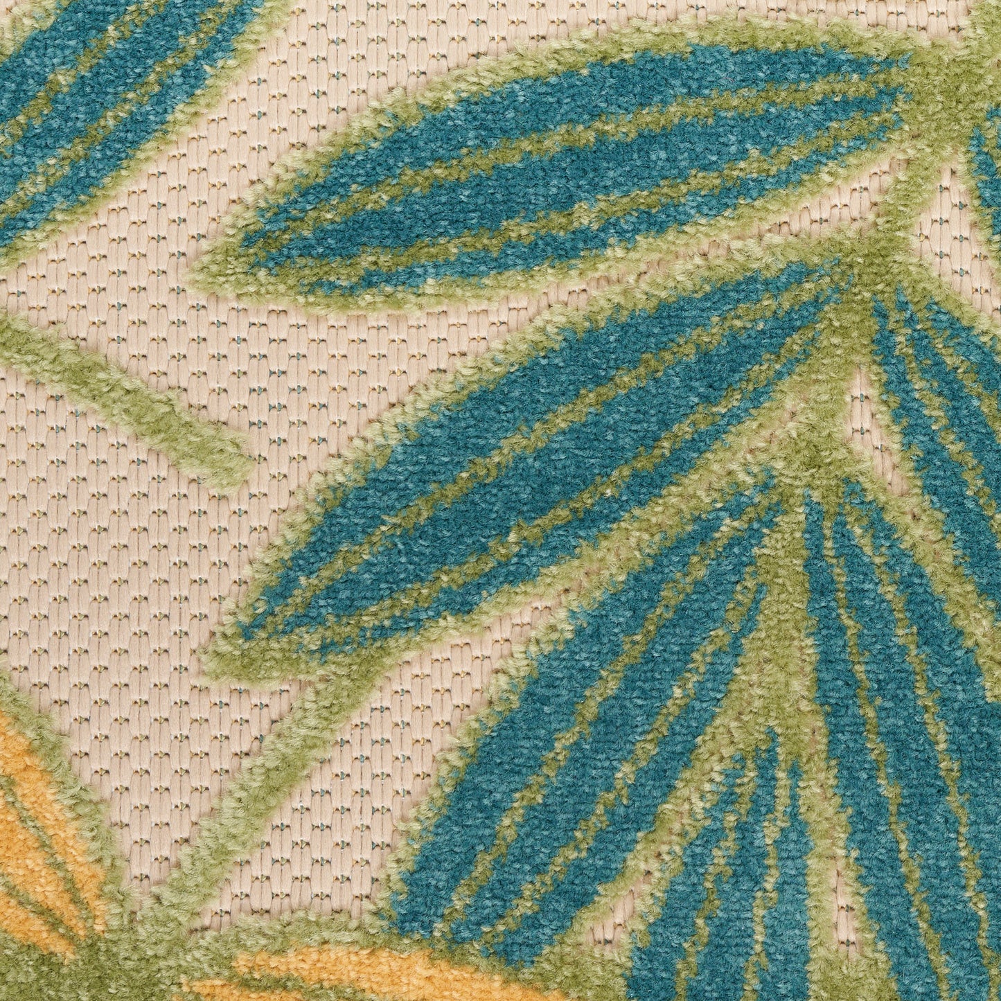 Close-up of a tufted rug with teal and lime-green leaf motifs on a beige woven background