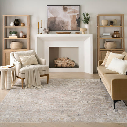 Cozy living room with a white fireplace, beige sofa and armchair, natural wood bookshelves, abstract art, and a muted rug.