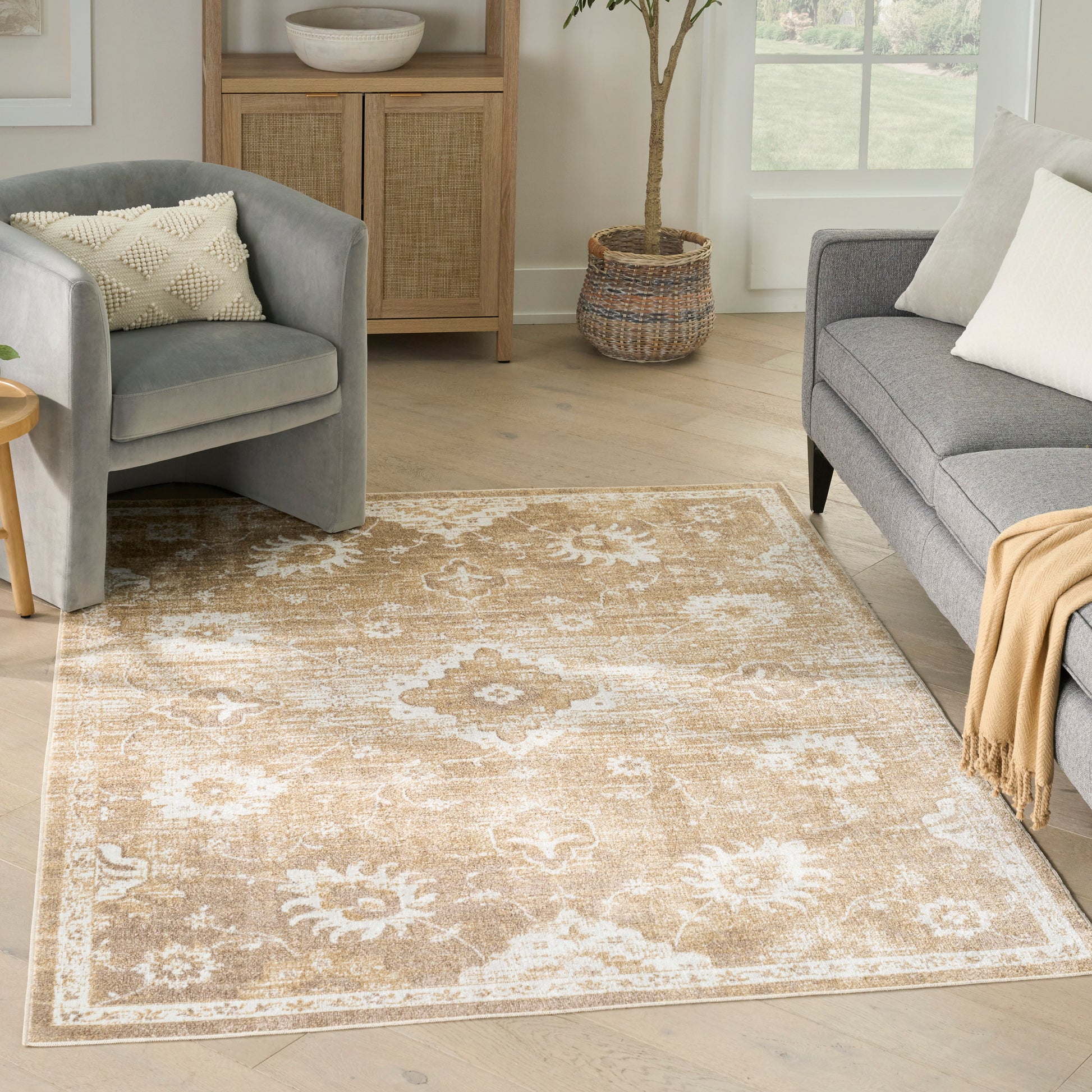 Beige traditional rug with white medallion motifs on light wood floor, flanked by gray sofas.
