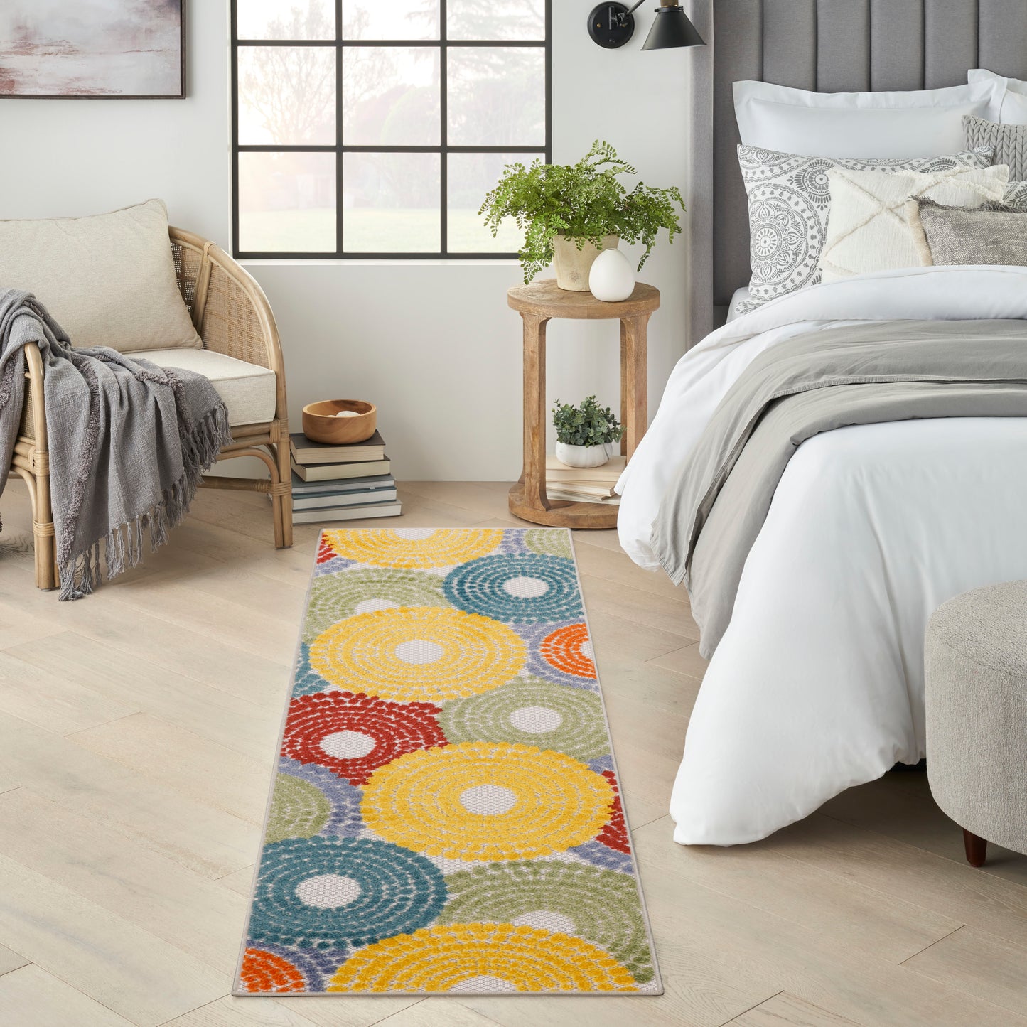 Long flat-weave runner with multicolor concentric circles in yellow, blue, orange and red, in a bright bedroom.