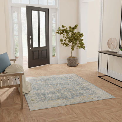 Entryway scene with a blue ornate rug on light wood floor, black front door with glass panels, potted tree and console table.