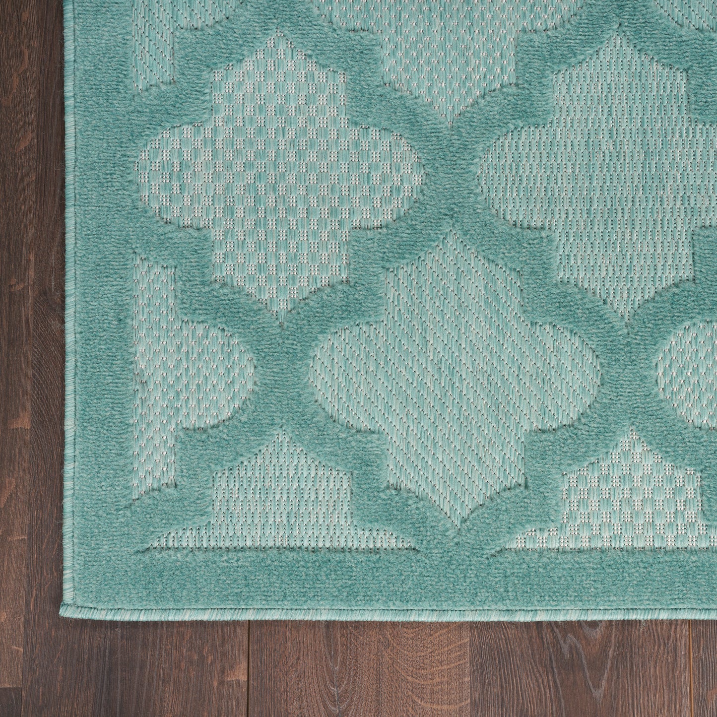 Teal woven outdoor runner rug with repeating quatrefoil motif, mint centers & darker teal outlines, bordered edge.