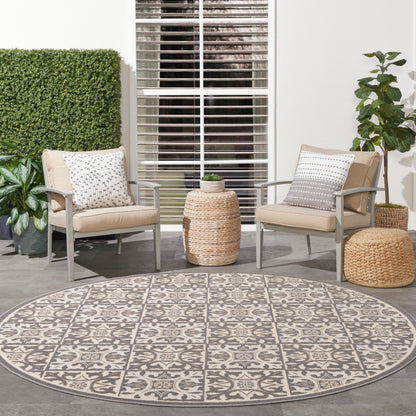 Round geometric outdoor rug, 8 ft diameter, shown on a patio with plants.