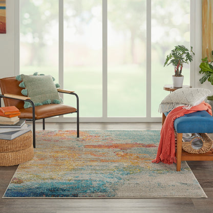 Bright living room with a colorful area rug, brown leather chair, blue cushioned bench, potted plant, and cozy throws.