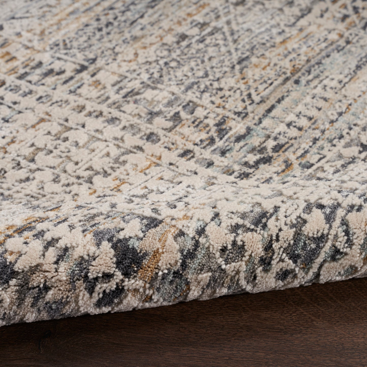 Textured area rug with a distressed geometric pattern in ivory, gray, navy and gold; low-pile and cozy.