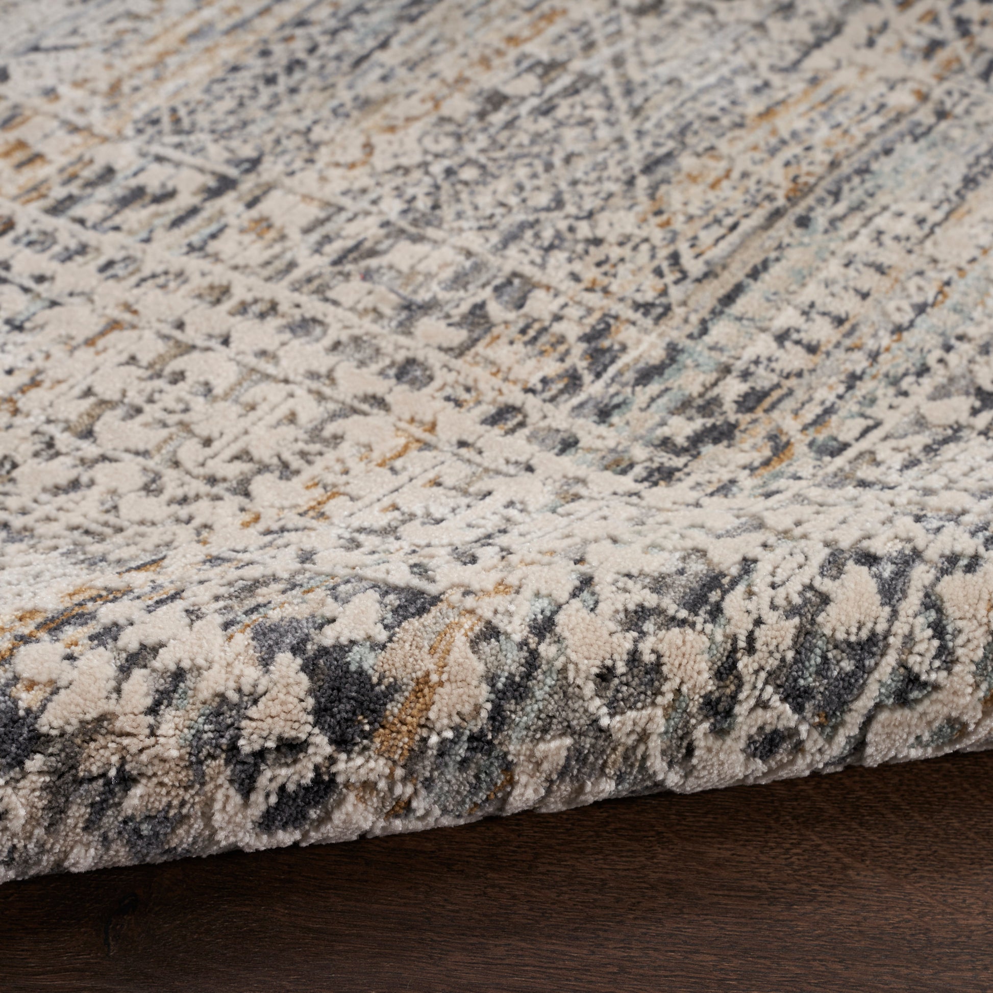 Textured area rug with a distressed geometric pattern in ivory, gray, navy and gold; low-pile and cozy.