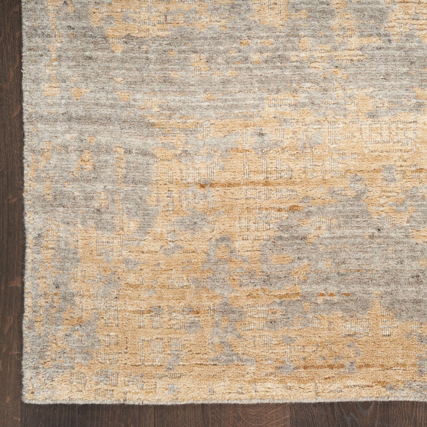 Rectangular gray and tan distressed-pattern area rug on dark wood floor.