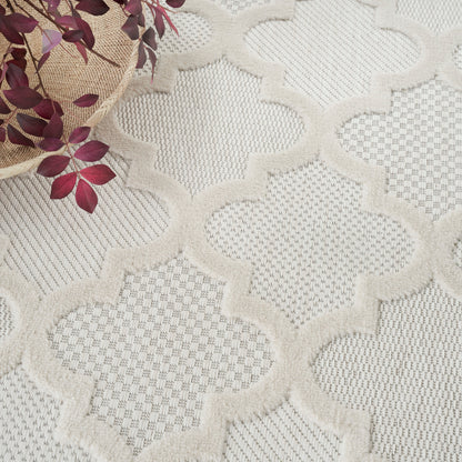 Beige textured rug featuring cream raised quatrefoil lattice pattern; woven basket with burgundy leaves resting on it.
