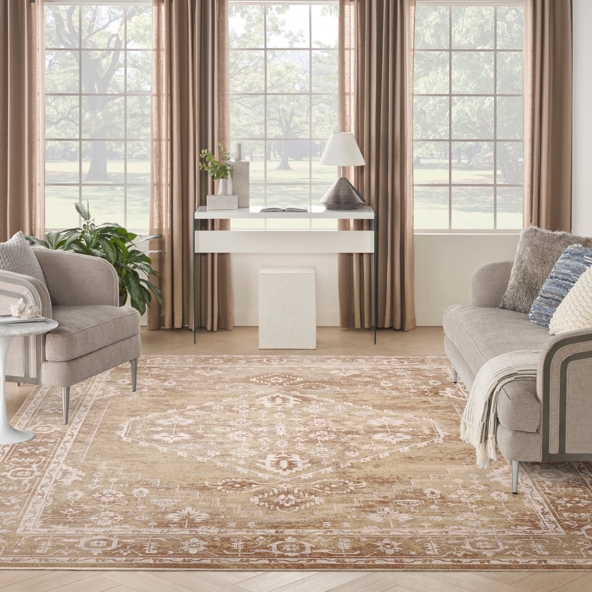 Neutral living room with beige curtains, glass-and-white console, gray upholstered chairs, and a patterned beige rug.
