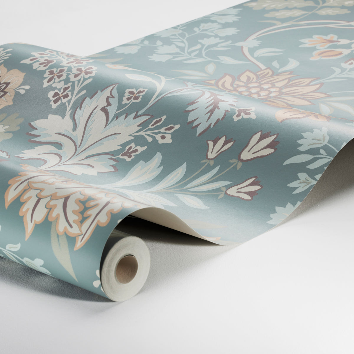 Rolled wallpaper with teal blue background and pale peach and ivory floral pattern, partially unrolled on white surface.