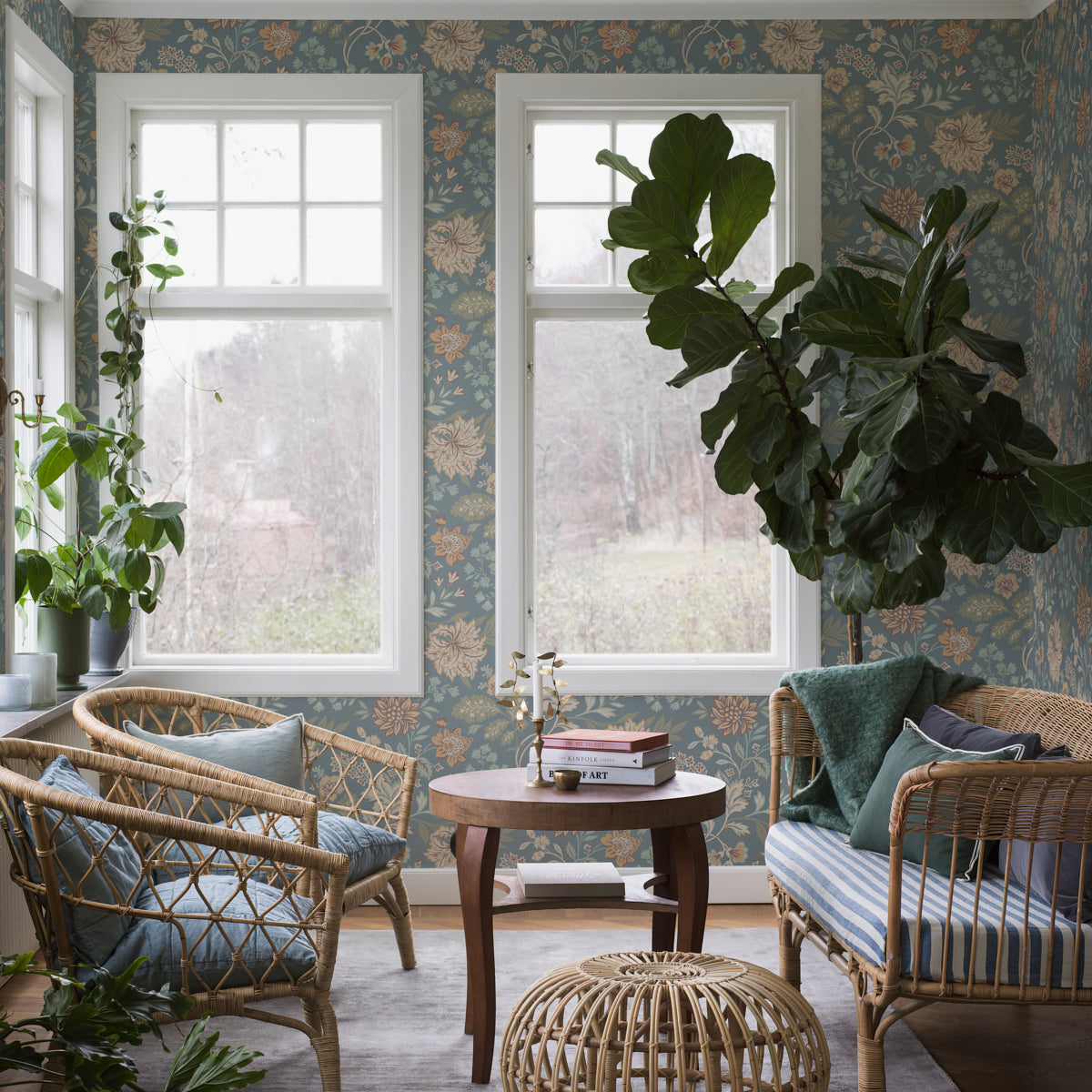 Boho living room with wicker chairs, round wooden coffee table, fiddle-leaf fig, blue floral wallpaper, striped cushions.