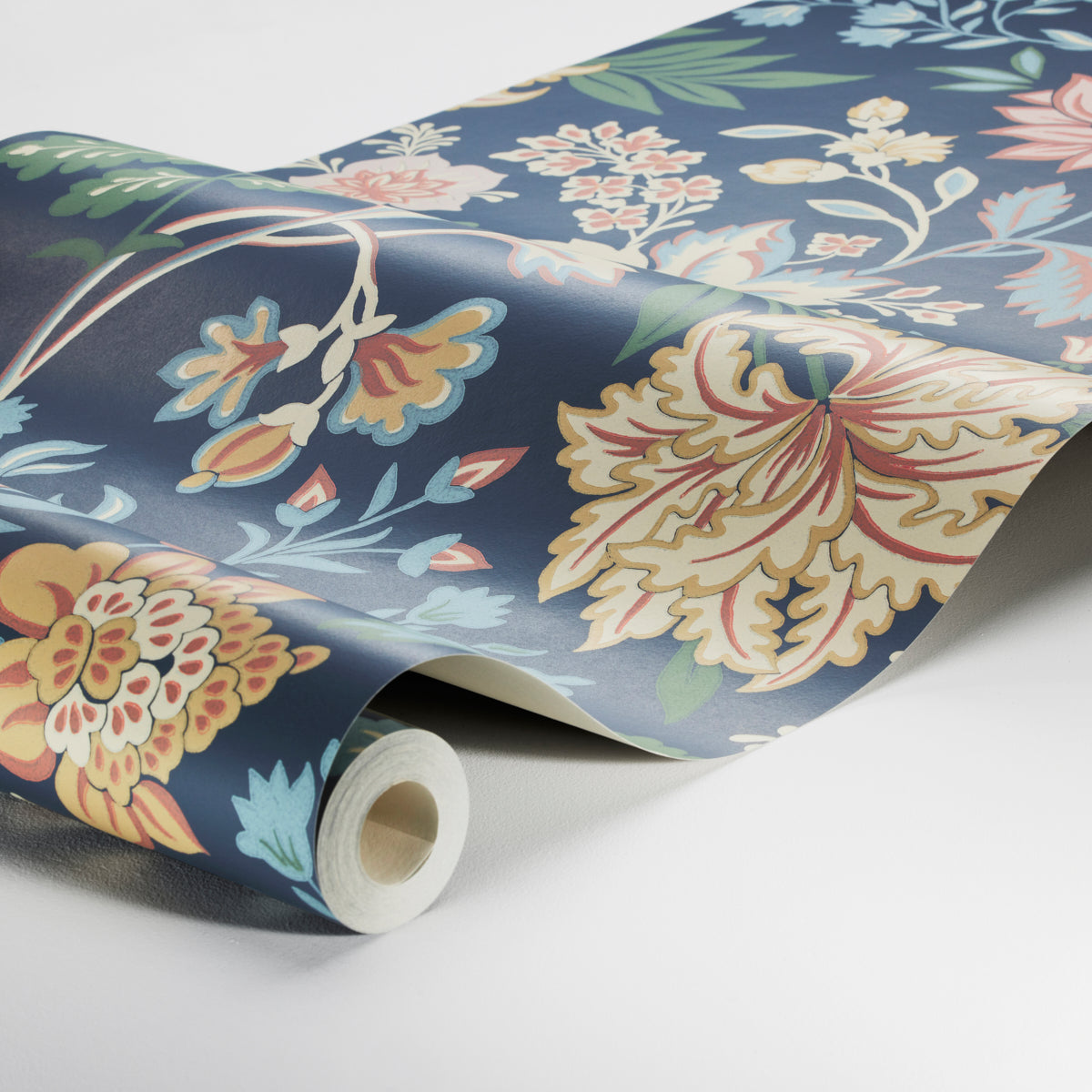 Roll of navy wallpaper featuring large pastel floral pattern in yellow, pink, cream and blue.