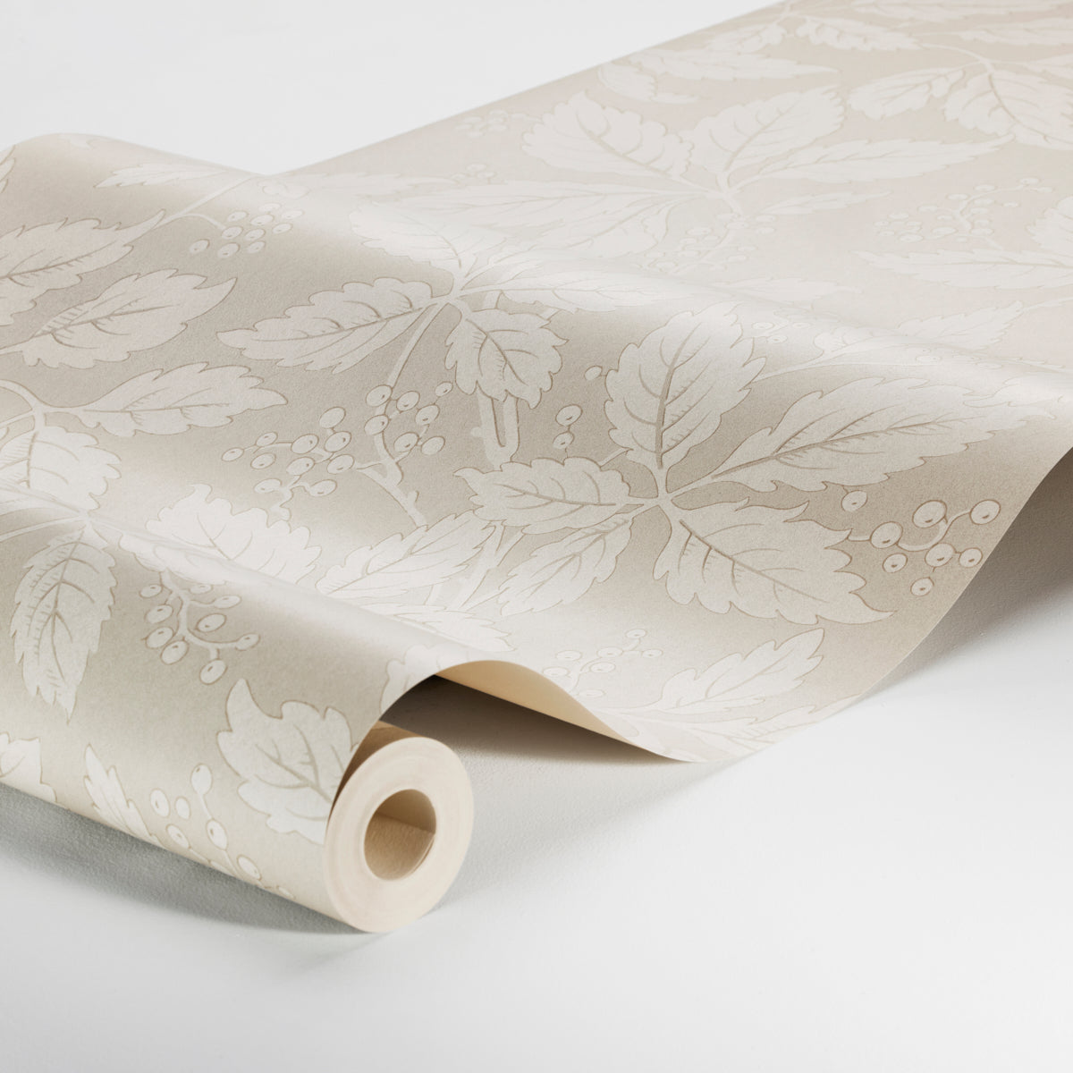 Beige wallpaper with white botanical leaves and berries in a damask pattern, rolled up.