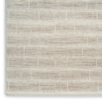 Cream-beige textured area rug with subtle geometric weave and fringe trim.