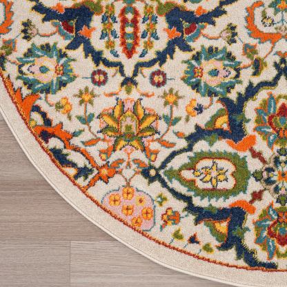 Round tufted wool oriental rug with cream backdrop and vivid floral motifs in orange, blue, green, pink on wooden floor.